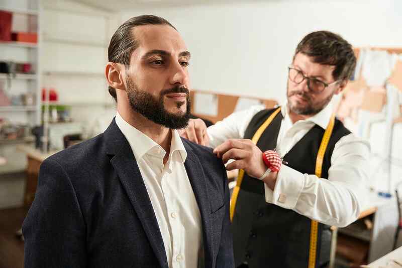 stock-photo-concentrated-couturier-trying-on-custom-made-suit-jacket-on-client-2254693109